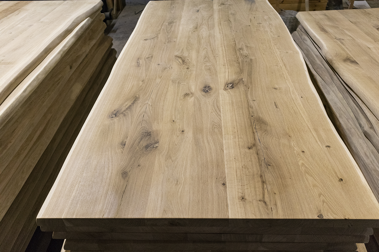 Piano tavolo in rovere con il bordo del tronco sui due lati lunghi.  Spessore 40 mm.